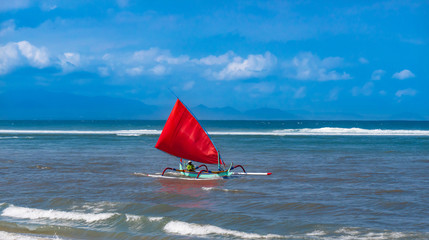 Red sail on a colorful traditional Balinese boat