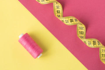 Bright yellow and pink background with contrasting spools of sewing thread.