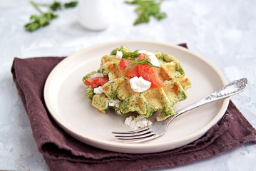 Light dinner, lunch or brunch, savory spinach snack waffles with salted salmon and cream cheese on a ceramic plate. Healhy food.