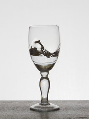 Spray liquid (clear water, red wine) from a glass goblet.