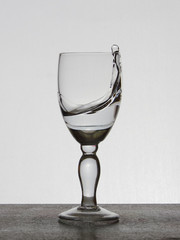 Spray liquid (clear water, red wine) from a glass goblet.