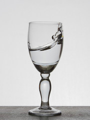 Spray liquid (clear water, red wine) from a glass goblet.