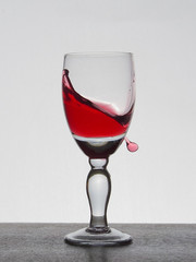 Spray liquid (clear water, red wine) from a glass goblet.