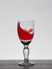 Spray liquid (clear water, red wine) from a glass goblet.