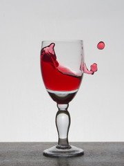 Spray liquid (clear water, red wine) from a glass goblet.