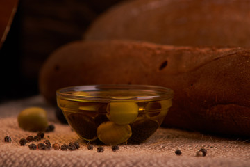 fresh bread baguette with olive oil, olives. cheese and rosemary on wooden background. Teasty breakfast