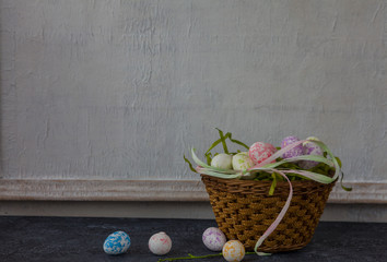 Easter composition on dark stone table and white vintage wall in background