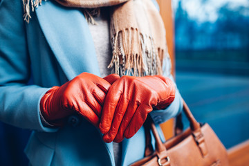 Elegant outfit. Closeup of of stylish woman in coat, scarf and brown gloves. Fashionable girl on the street. Female fashion.