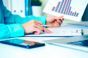 Business woman working with financial data holding sheet of paper with financial figures in hand and make notes in clipboard. Business financial and accounting concept.