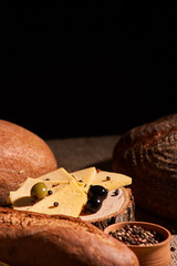 Slices of cheese on wooden desk between different breads. place for text