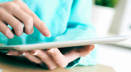 Close-up of female hands working with tablet computer. Woman using social network, texting and blogging.