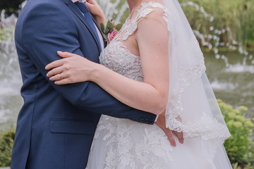 bride and groom are hugging in the park