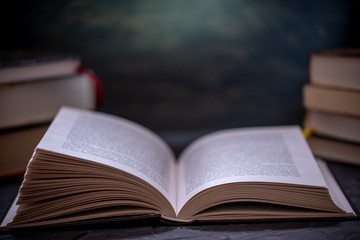 Open book on a stack of books on a table on a dark background. Education and reading of paper books