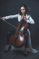 Beautiful woman in a white coat plays the cello