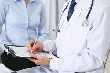 Male doctor holding application form while consulting female patient in hospital. Medicine and healthcare concept