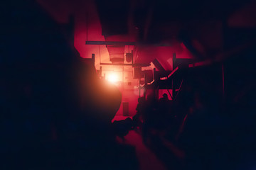 Silhouettes of people inside dark room of underground military bunker or bomb shelter in red light...