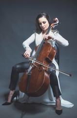 Fototapeta na wymiar Beautiful woman in a white coat plays the cello