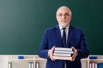 Aged male teacher in front of chalkboard 