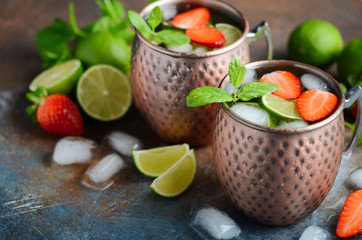 Moscow mule cocktail with ginger beer, vodka, lime, strawberries and mint in a cooper mugs.