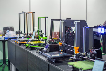 Automatic 3D printers in row during work at modern technology exhibition. 3D printing, additive technologies, 4.0 industrial revolution and futuristic concept