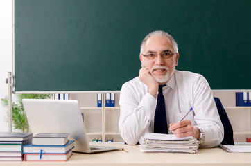 Aged male teacher in front of chalkboard 