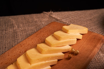 Traditional Dutch semi hard cheese served close up on rural table with sacking. Selective focus