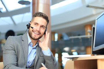 Smiling friendly handsome young male call centre operator.