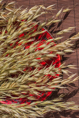 Reap of oats on a red plate. Brown background. Top view.