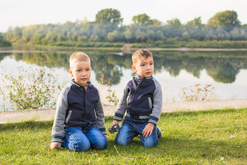 Children and nature concept - Two brothers sitting on the grass over nature background