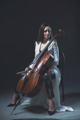 Beautiful woman in a white coat plays the cello