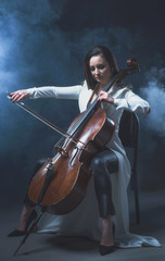 Beautiful woman in a white coat plays the cello