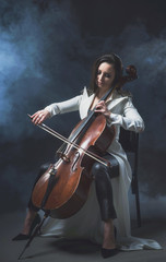 Beautiful woman in a white coat plays the cello