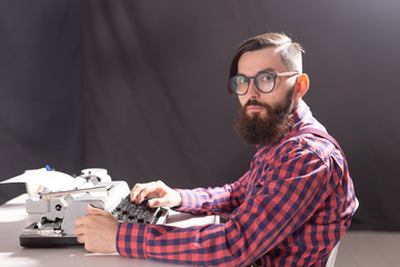 People and technology concept - Side view handsome man with beard working on typewriter over black background