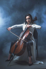 Beautiful woman in a white coat plays the cello