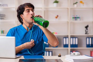 Young male doctor drinking in the office 