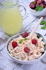 Cottage cheese topped with raspberries in a bowl on white wooden table