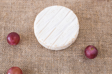 Brie or camembert cheese with grapes on rustic background top view