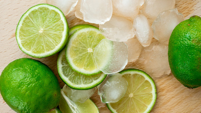 Limonka leżąca na drewnianej desce w otoczeniu wody i lodu