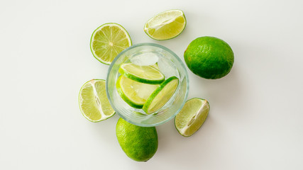 Woda z limonką w otoczeniu pokrojonej limonki na białym tle © PhotoHunter