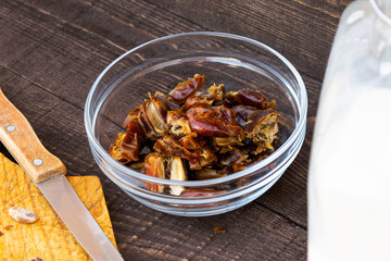 Hushaf - date milk, traditional ramadan dish, cooking, ingredients, pitted dates in a plate, knife and seeds on a cutting board and milk in a bottle stand on a wooden table