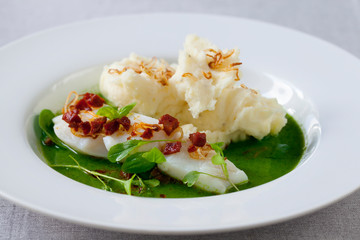 Butter poached cod with green peas, spinach and basil veloute, crispy chorizo and shallot
