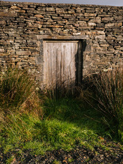 Ancient wooden doorway in stone building in rural Ireland