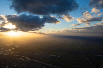 Beams of sun going through cloud onto evening land
