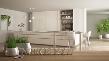 Wooden table, desk or shelf with potted grass plant, house keys and 3D letters making the words interior design, over blurred modern kitchen, project concept copy space background