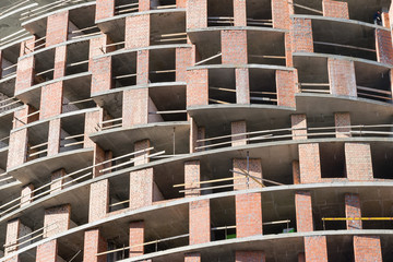 wall with window openings in a multi-storey high-rise residential building under construction from concrete and brick