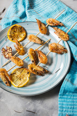 Grilled shrimp skewers with herbs, garlic and lemon on concrete background. Seafood