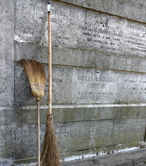 Zwei Reisigbesen an einer Friedhofsmauer 