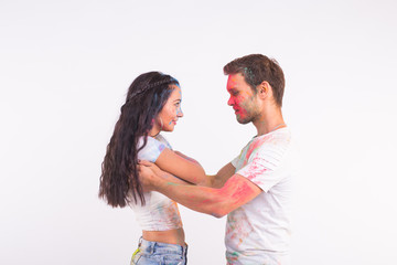 Holiday, social dance, holi and people concept - Happy couple having fun and dancing bachata or kizomba with multicolored powder on their faces on white background