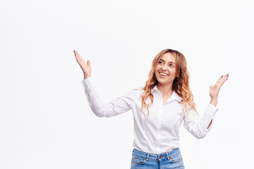 Happy surprised  young woman smiling broadly at camera, pointing fingers up, showing something interesting and exciting on white background with copy space for text or advertising content