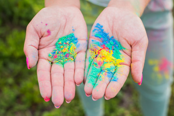 Holi festival and color concept - Hands with yellow, blue, green colours
